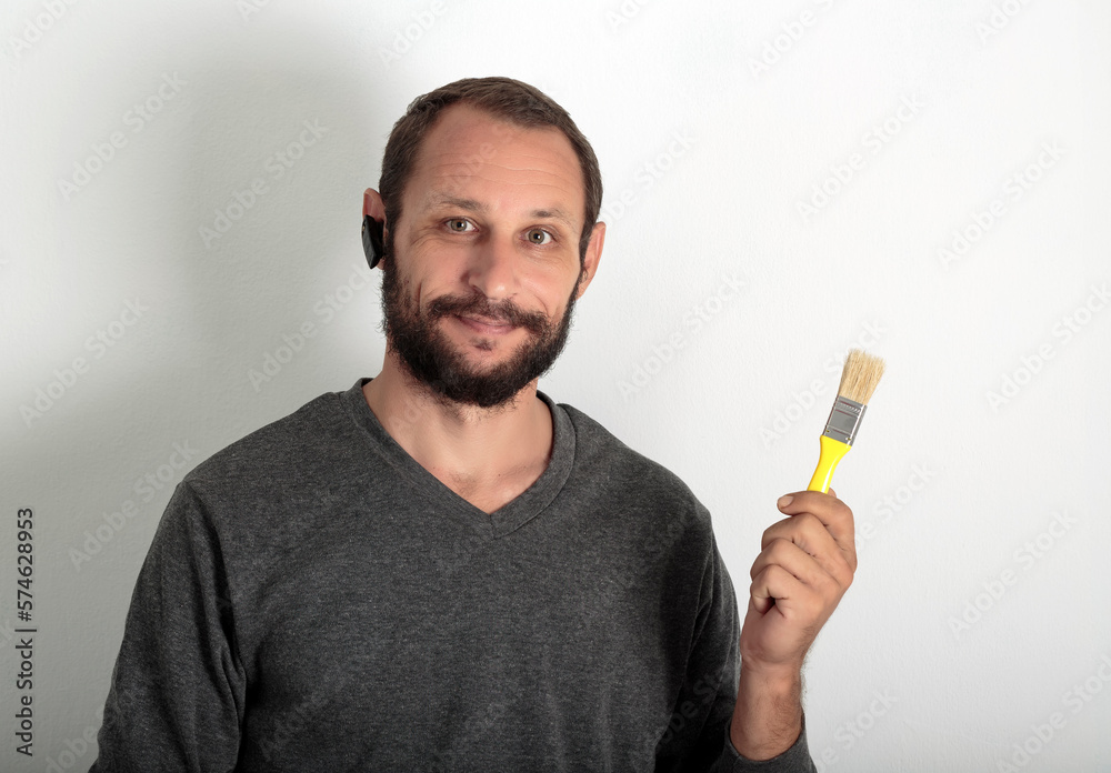 Bearded man working. Caucasian painter worker holding paint brush and looking forward. Happy painter in working clothes hold paint brush painting tools for building and construction work, finishing. Bearded man working. Caucasian painter worker holding paint brush and looking forward. Happy painter in working clothes hold paint brush painting tools for building and construction work, finishing.