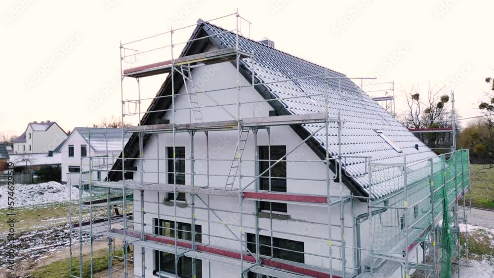 Crane shot of a single-family home with scaffolding in winter