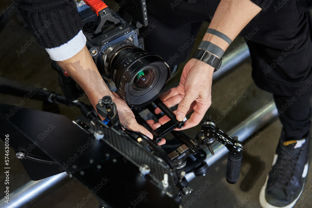male hands of a cameraman adjust the body kit of a professional movie camera before filming