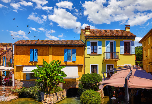 Old village Borghetto Valeggio sul Mincio, Veneto region, Italy. Colorful houses. Panoramic view at the town house on river. Sunny day with blue sky and clouds