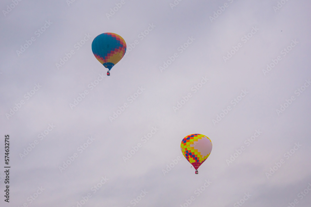 Two colorful hot air balloons flying against grey sky at Winter aerostat festival. Freedom, sport, aircraft concept Two colorful hot air balloons flying against grey sky at Winter aerostat festival. Freedom, sport, aircraft concept