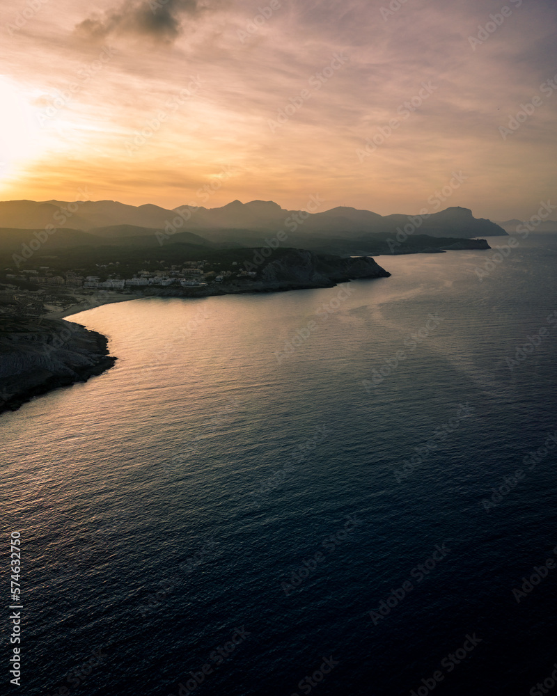 View over the shoreline of Mallorca, Spain, on a sunny afternoon in Summer with beautiful rock formations in the back during blue hour facing the sunset
