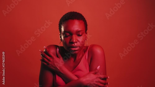 Cold gesture. Chilly weather. Flu fever. Red neon color light shivering freezing sick woman embracing shoulders keeping warmth isolated on dark bright gif loop boomerang animation.