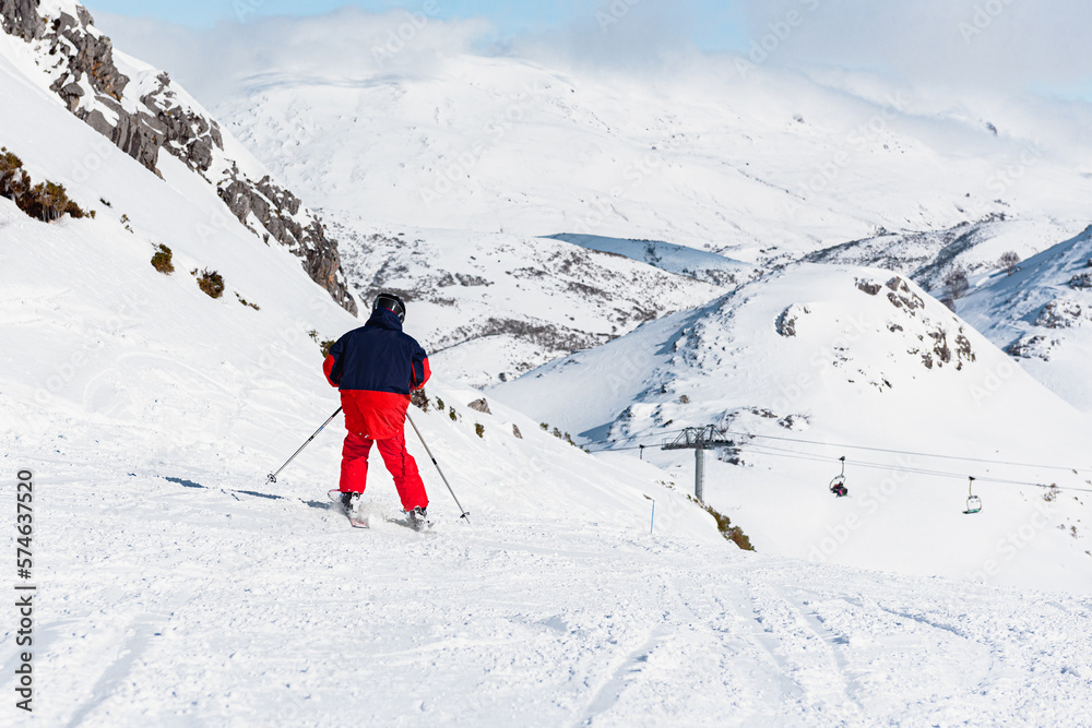 Defying the slope: an unrecognizable person with his back turned in red clothes skiing on the mountain. winter sports. 