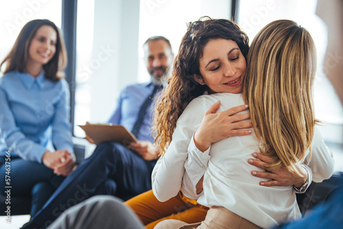 Foto Young adult woman embracing and supporting friend during support group therapy session with diverse women