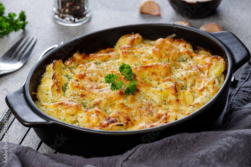 Potato casserole with cheese and parsley on stone background. French cuisine.