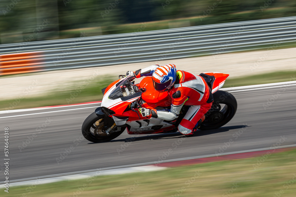 A motorcycle rider riding on an white,orange sport motorcycle through a corner at high speed. Leaning from the bike and dragging a knee.  - obrazy, fototapety, plakaty 