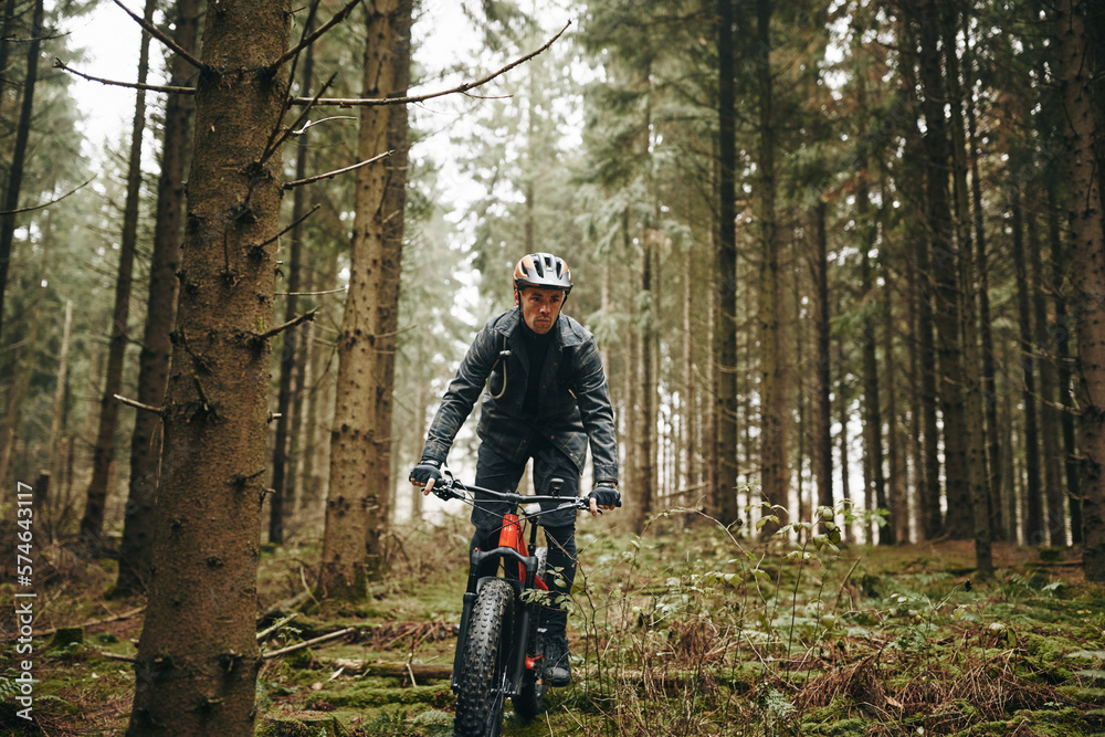 Man riding his mountain bike along a rugged forest trail Man riding his mountain bike along a rugged forest trail