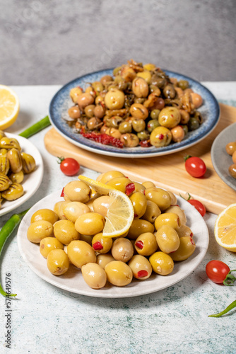 Olive varieties. Assortment of black and green olives on plate on gray background. Close up