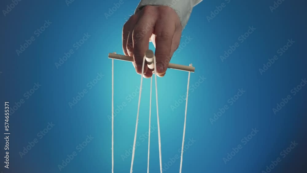 The puppeteer's hand controls the puppet with a wooden manipulator and strings. The