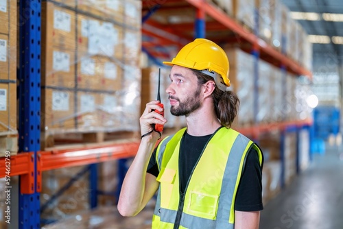 Warehouse worker standing radio walkie call to team during stock check in storage area