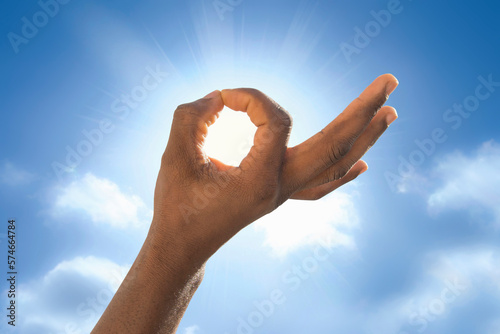 Man trying to hide the sun with an open hand. Climate change: symbolic representation of the ozone hole. Photo