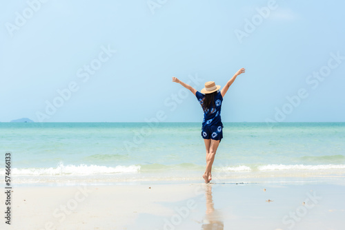Summer vacations. Lifestyle man raise arm relax and chill on the rock  blue beach and sky background.  Asia happy young people standing near the wave sea  summer trips enjoy tropical beach