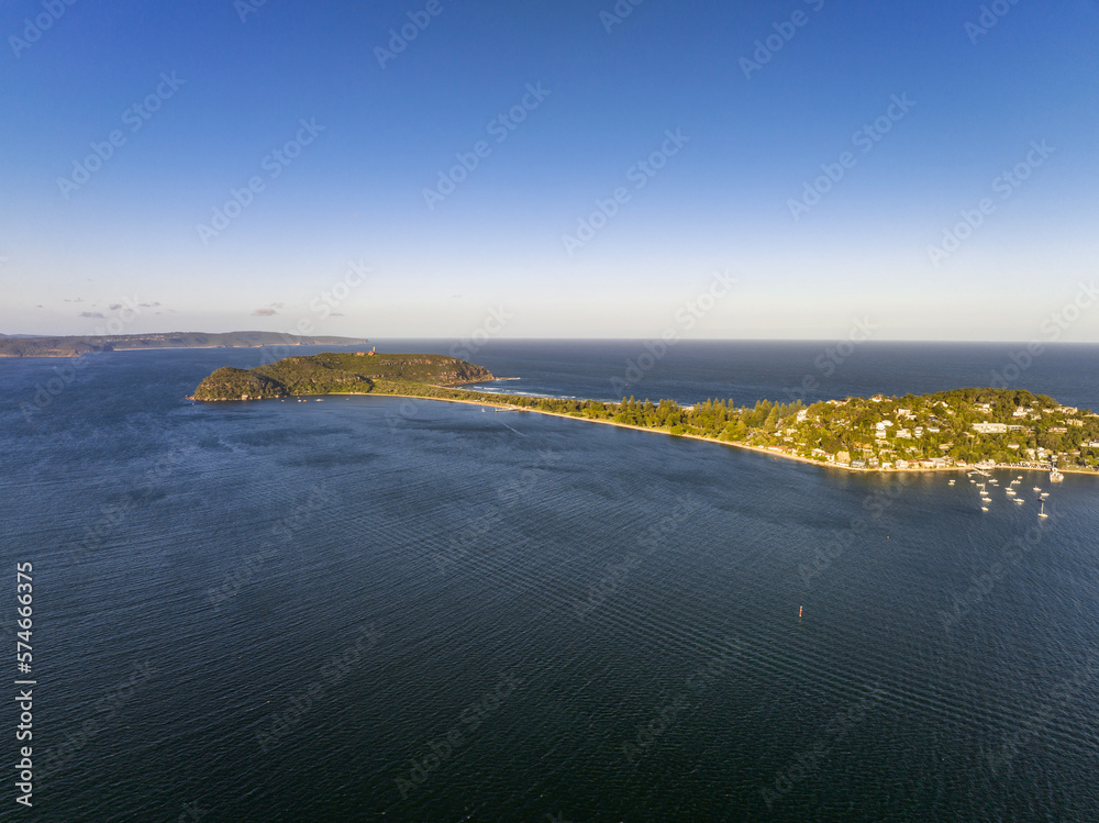 High angle aerial evening drone view of Palm Beach and Barrenjoey Head and Lighthouse. Palm Beach is an affluent beachside suburb in the Northern Beaches region of Sydney, New South Wales, Australia.