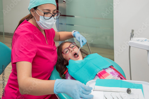 Girl with her mouth open while her dentist gives her oral treatment