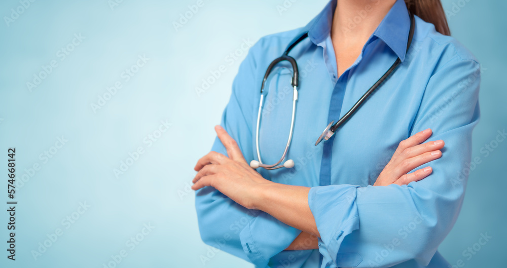 Female doctor in lab coat with arms crossed on blue background. Copy space