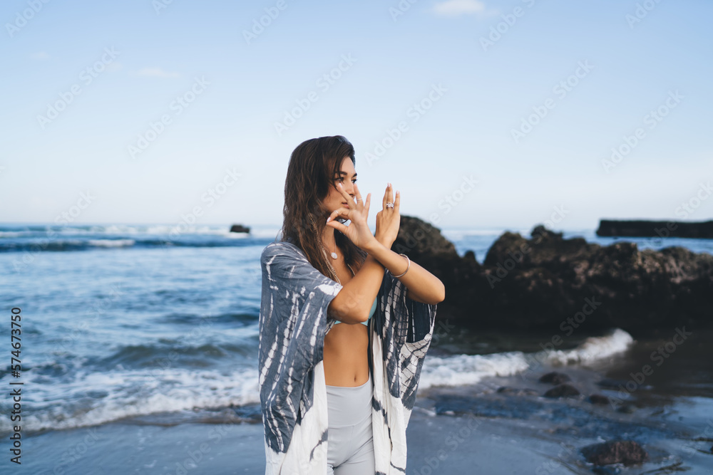 Cheerful woman with hands crossed and standing on beach