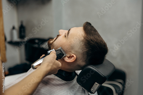 A close-up photo of a man's beard haircut. A barber cuts a beard in a barbershop. Beard trimming in a beauty salon for men