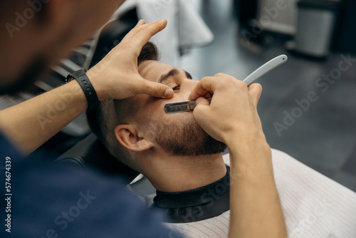 The process of trimming a man s beard with a dangerous razor. A barber cuts a beard in a barbershop. Beard trimming in a beauty salon for men
