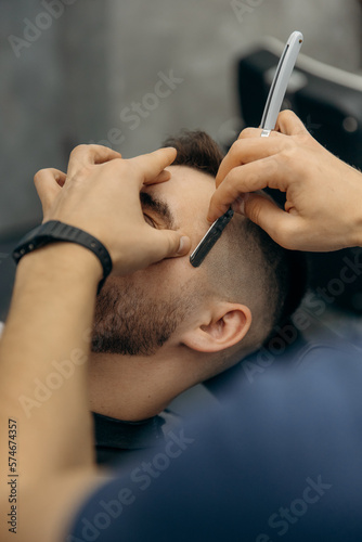 close up photo of trimming a man's beard with a dangerous razor. A barber cuts a beard in a barbershop. Beard trimming in a beauty salon for men