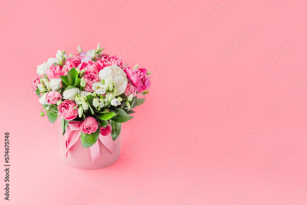 Arrangement of flowers in a hat box. Bouquet of peonies, eustoma, spray rose in a pink box with an oasis on a pink background