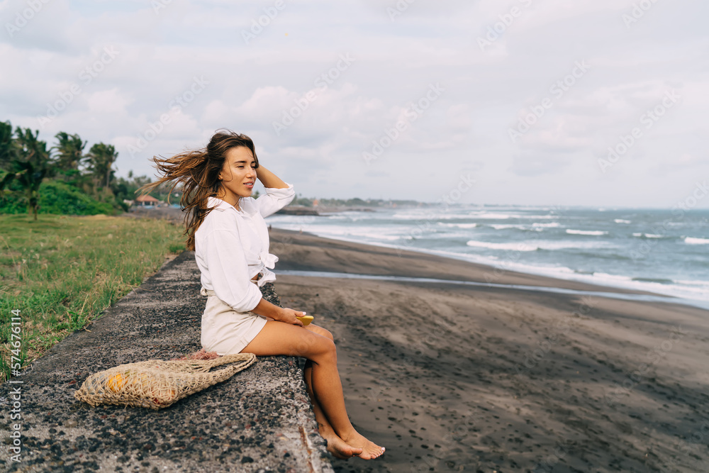 Delighted woman chilling on coast of ocean