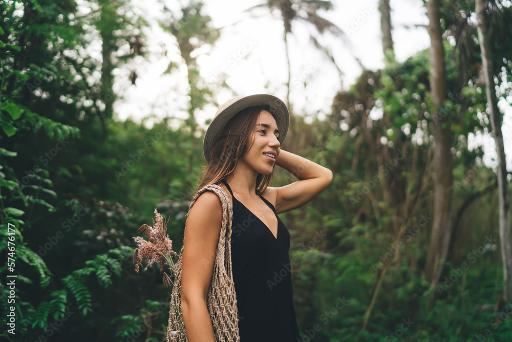 Smiling woman in hat with eco friendly bag standing in forest Smiling woman in hat with eco friendly bag standing in forest
