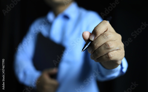 A man with clipboard is reachout pen to writing infront of him, represent to record or note something happend.