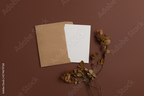 Mockup of an open card made of kraft paper and decorated with a composition of dried blueberry branches placed on a brown background