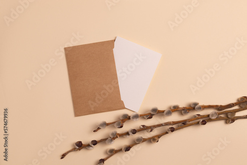 Mockup of an open invitation card made from eco-friendly craft paper and decorated with a composition of dry flowering branches placed horizontally on a beige background