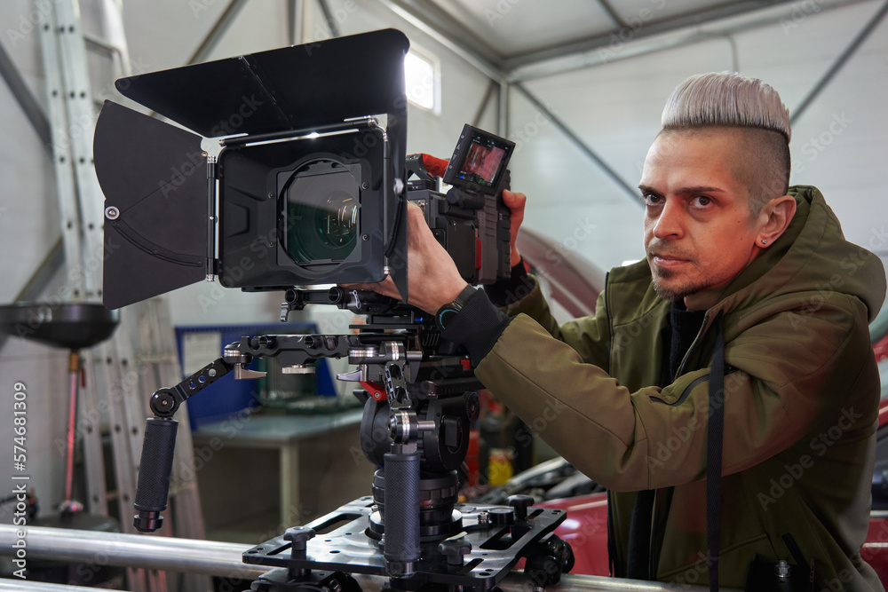 young caucasian man videographer controls filming on a professional movie camera that stands on a camera trolley and rails young caucasian man videographer controls filming on a professional movie camera that stands on a camera trolley and rails