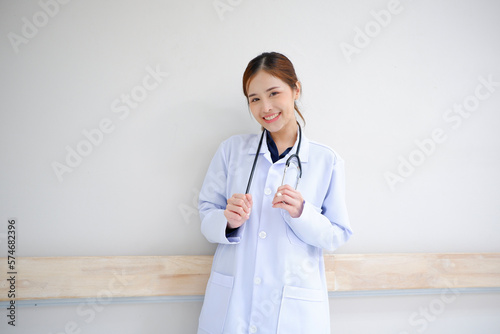 Smiling Asian female doctor in medical gown with stethoscope on her shoulder medical concept.