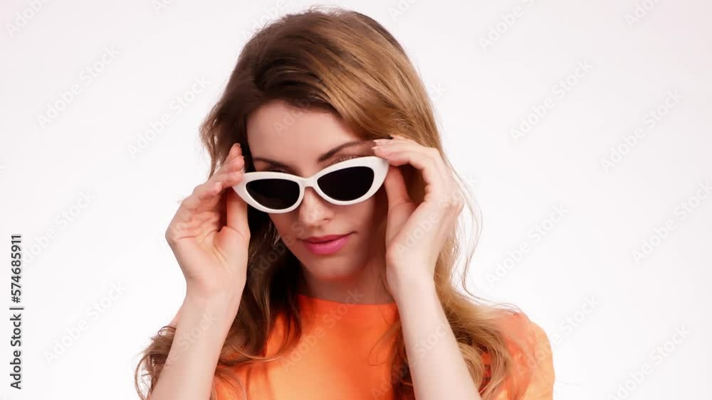 Woman smiling looking at camera. Happy positive emotional blonde girl in sunglasses. Cheerful lady smile face, beauty self-love concept. Indoors studio, pretty young lady isolated on white background Woman smiling looking at camera. Happy positive emotional blonde girl in sunglasses. Cheerful lady smile face, beauty self-love concept. Indoors studio, pretty young lady isolated on white background