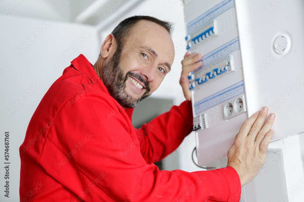 happy male electrician working on fusebox