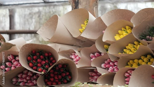 A bouquet of tulips in craft paper lies on the table.A gift to a girl for a holiday