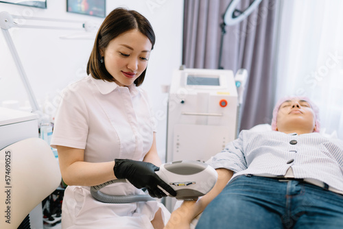 Positive Asian woman working with client in beauty clinic