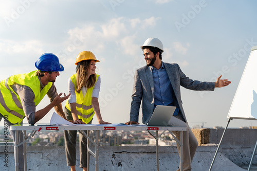 Diverse team of specialists with computer on construction site. Building project with engineers