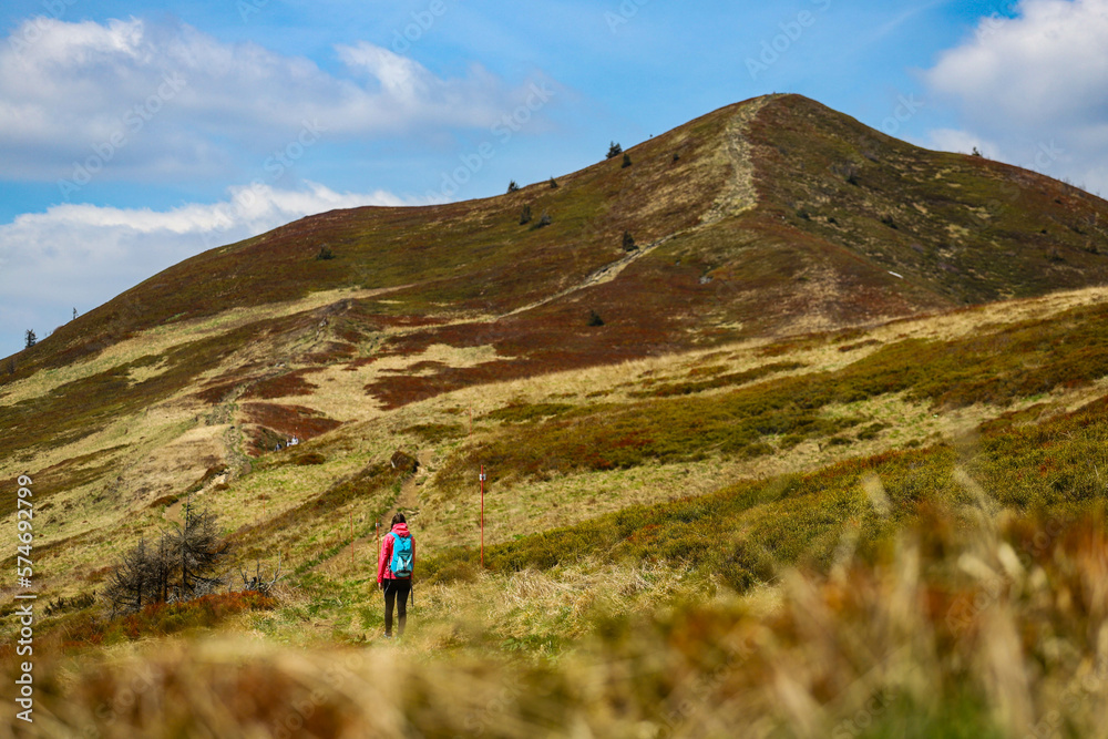 Obraz premium Beautiful fit happy girl in pink jacket enjoys hike in stunning colorful mountain scenery. Spring in the Bieszczady Mountains, Poland, Europe