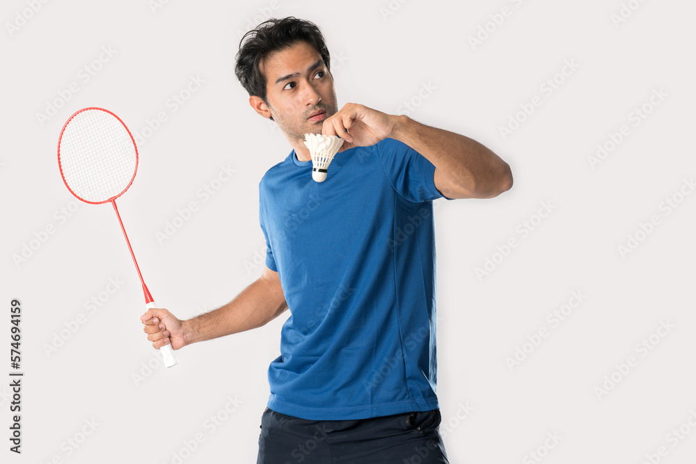 A badminton player in sportswear stands holding a racket and shuttlecock. A badminton player in sportswear stands holding a racket and shuttlecock.