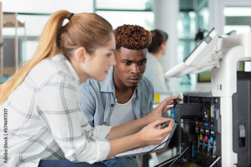female and male technician fixing a printer female and male technician fixing a printer