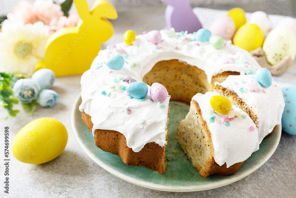 Glazed easter lemon cake decorated with confectionery and mini chocolate eggs candy on gray stone background. Happy Easter holidays, tasty dessert.