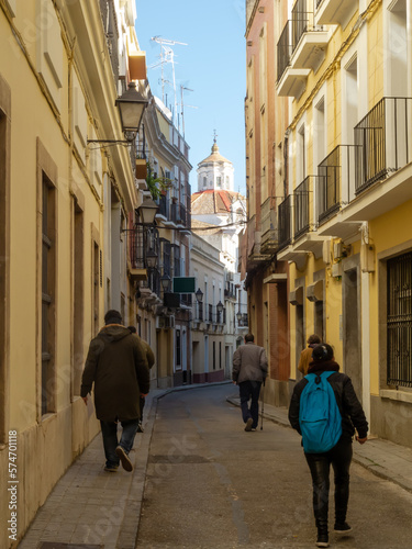 Gente paseando por el barrio histórico de una ciudad europea con edificio histórico al fondo.
