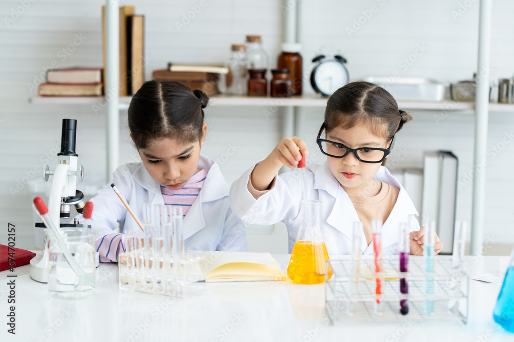 Two Asian girls standing in a science room, mixing paints, doing chemistry experiments. One person8 keeps a record of the experiment. and another person mixes the paint in another glass tube Two Asian girls standing in a science room, mixing paints, doing chemistry experiments. One person8 keeps a record of the experiment. and another person mixes the paint in another glass tube
