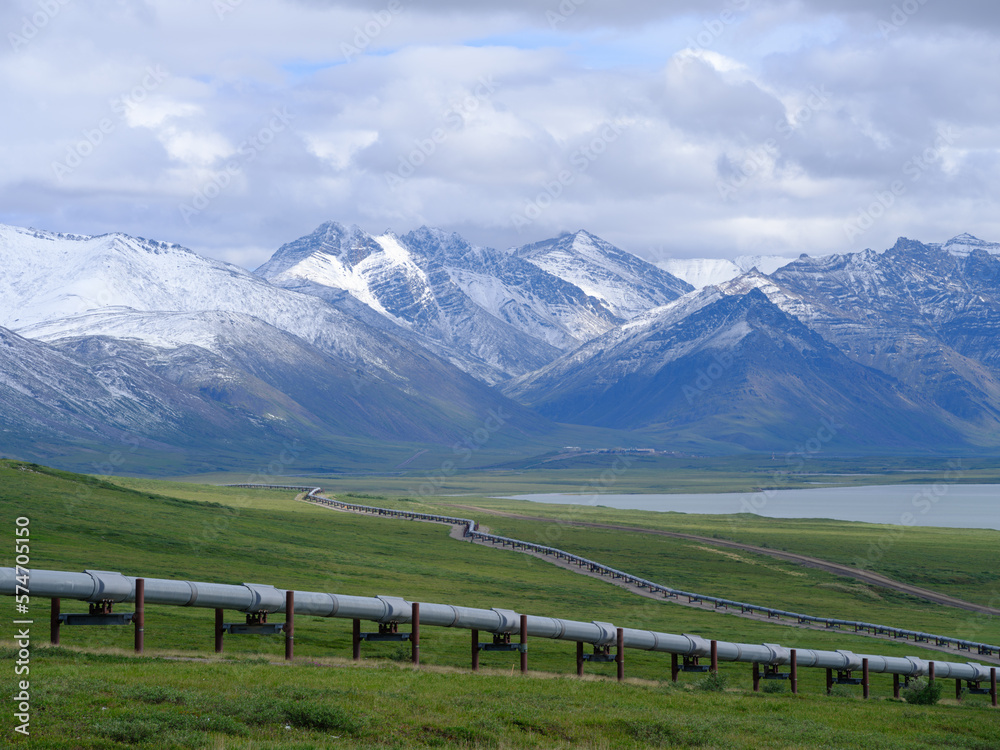 Fototapeta premium Fresh July snowfall on the mountains of the Brooks Range with the Alaska Oil Pipeline in the foreground traversing miles of empty Tundra