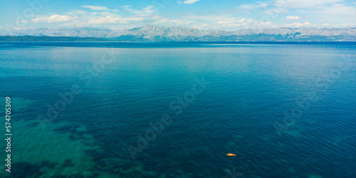 Girl in bikini on red watermelon mattress floats far from shore in the middle of the Mediterranean Sea, Pelješac Peninsula. Holiday in Croatia.  © Jakub