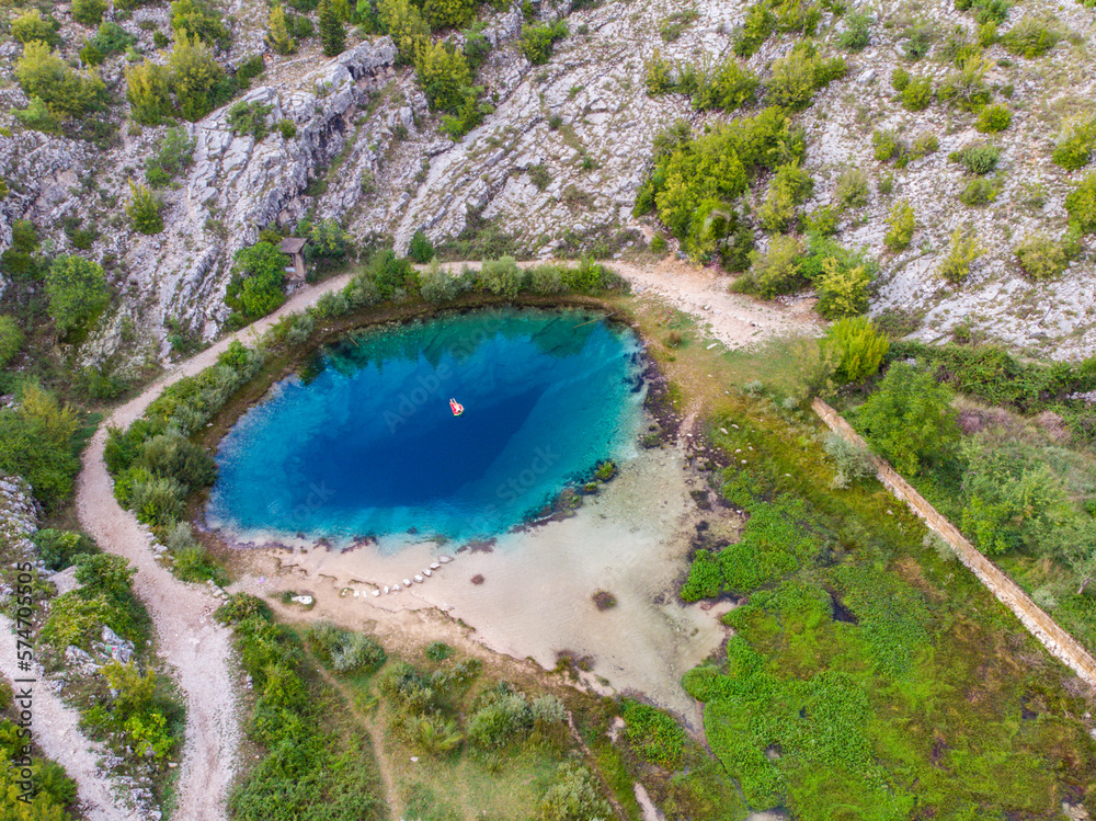 girl in a white bikini swims on a mattress in the spring of the river cetina in croatia, a unique deep river spring with crystal clear water