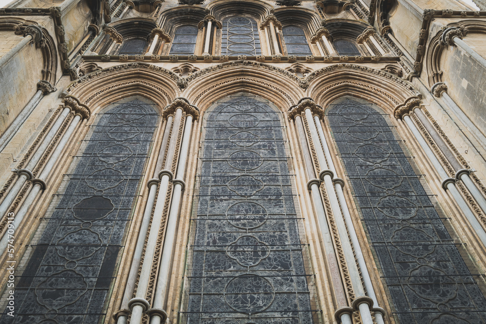 Magnificent vertical view of the tall leaded and stain glass windows of an English cathedral. Showing the ornate stonework.