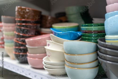 Deep bowls of different colors on the shelves of the store. Variety of plates displayed on shelves in a hardware store. Kitchen utensils and cutlery for sale