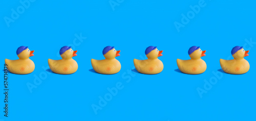 Yellow toy duckling for bathing on the blue background. Pattern. Flat lay. Copy space.