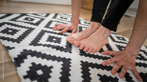 Close up on bare foot feet and hands of unknown caucasian woman stand in her apartment on the modern floor copy space yoga and stretching healthy lifestyle self care inner balance concept